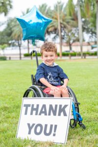 Young boy in wheelchair with thank you sign
