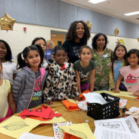 Children and staff smile in front of an art project